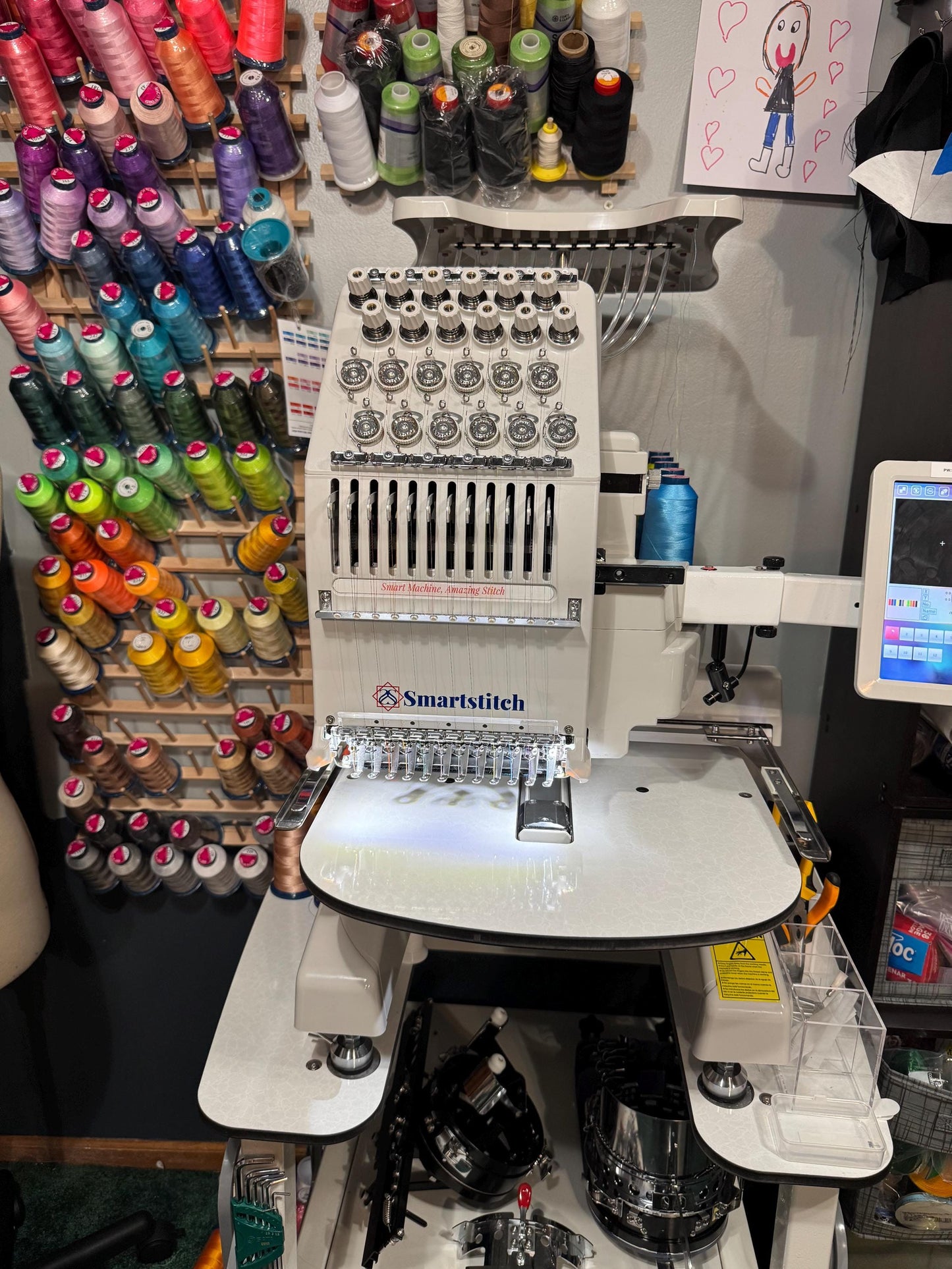 Smartstitch embroidery machine with various colored thread spools in the background