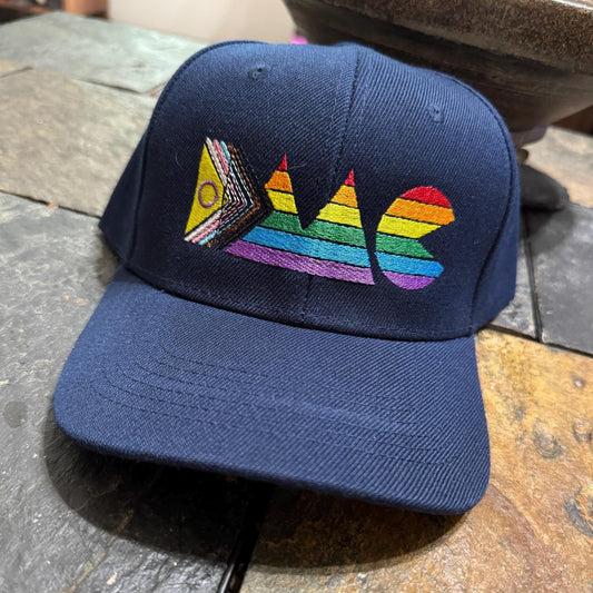 Navy blue cap with rainbow IMC design on a stone surface