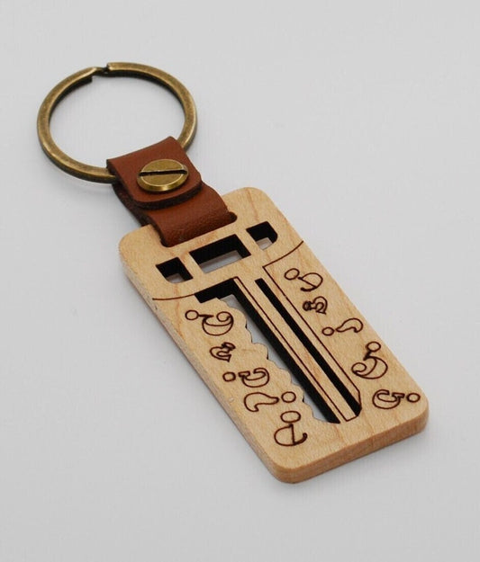 Wooden keychain with a key design and brown leather strap on a light gray background