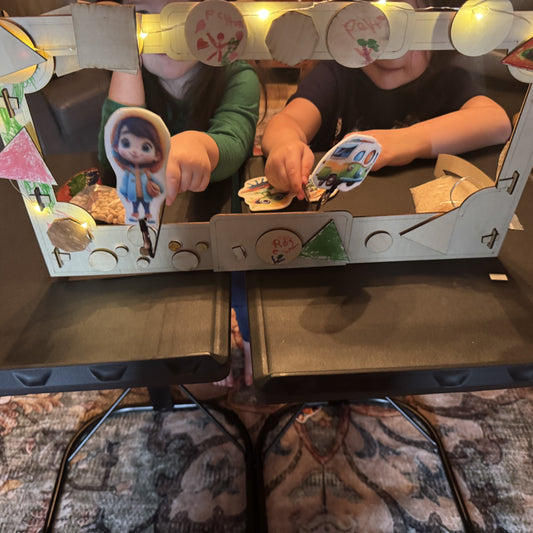 Two kids putting on a puppet show with the decorated wooden tabletop puppet theater, using the felt stick puppets on rods