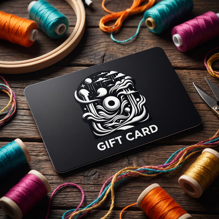 Black Its Not Nought gift card with a white logo, surrounded by colorful embroidery thread spools.
