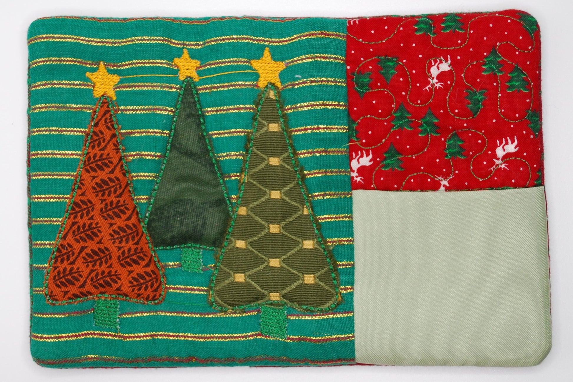 A mug run with patchwork with Christmas trees and patterns on a teal, red, and green background.