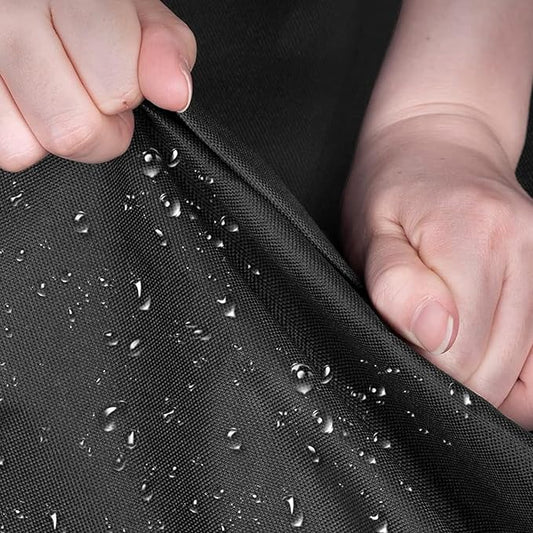 Person holding black fabric with water droplets, demonstrating water resistance.