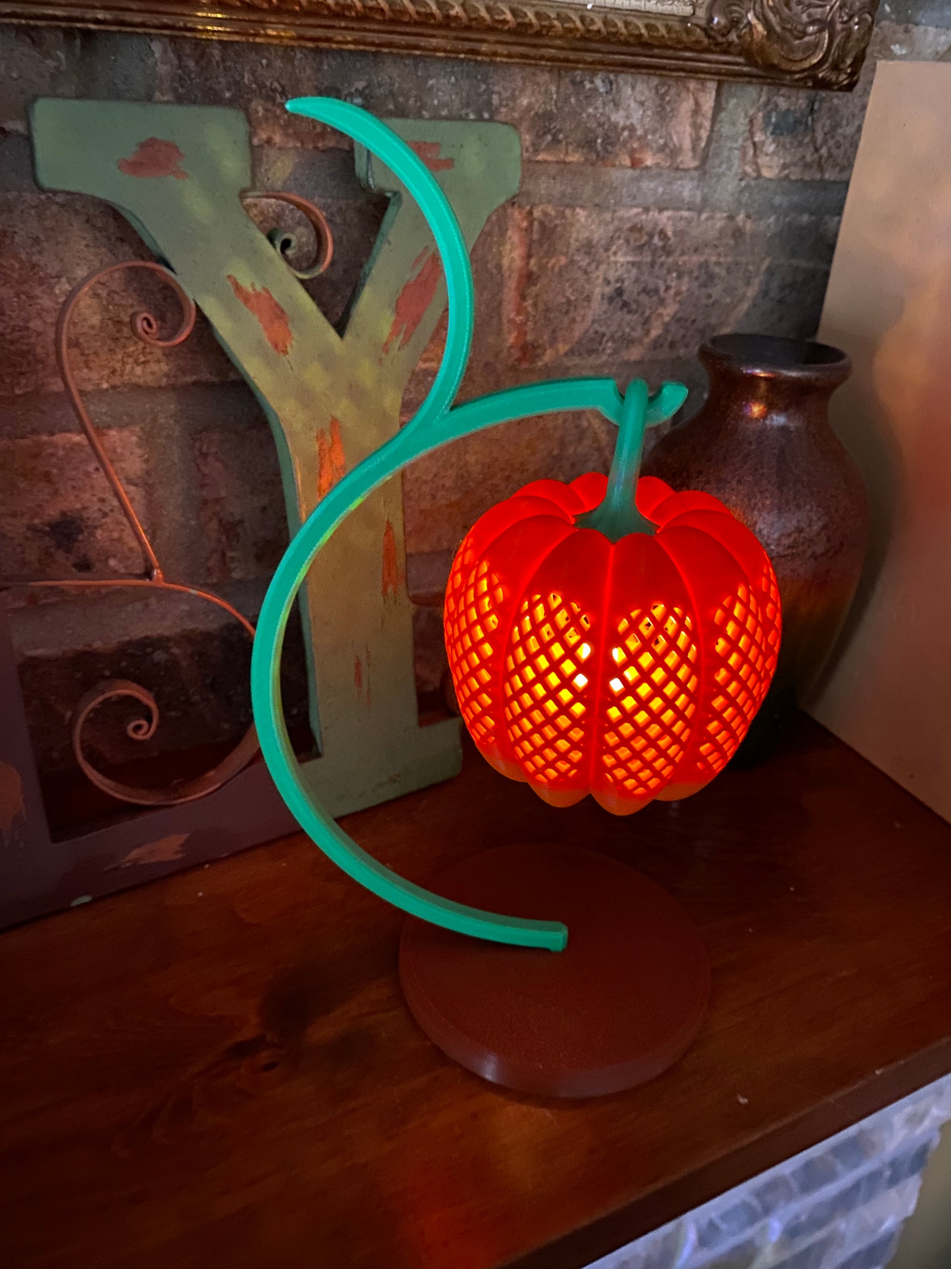 Orange pumpkin lantern glowing on a green vine stand, Halloween and fall decor lit by an LED tea light