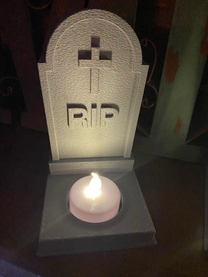 Rounded tombstone tea light holder with engraved cross and RIP, LED tea light glowing in the base recess