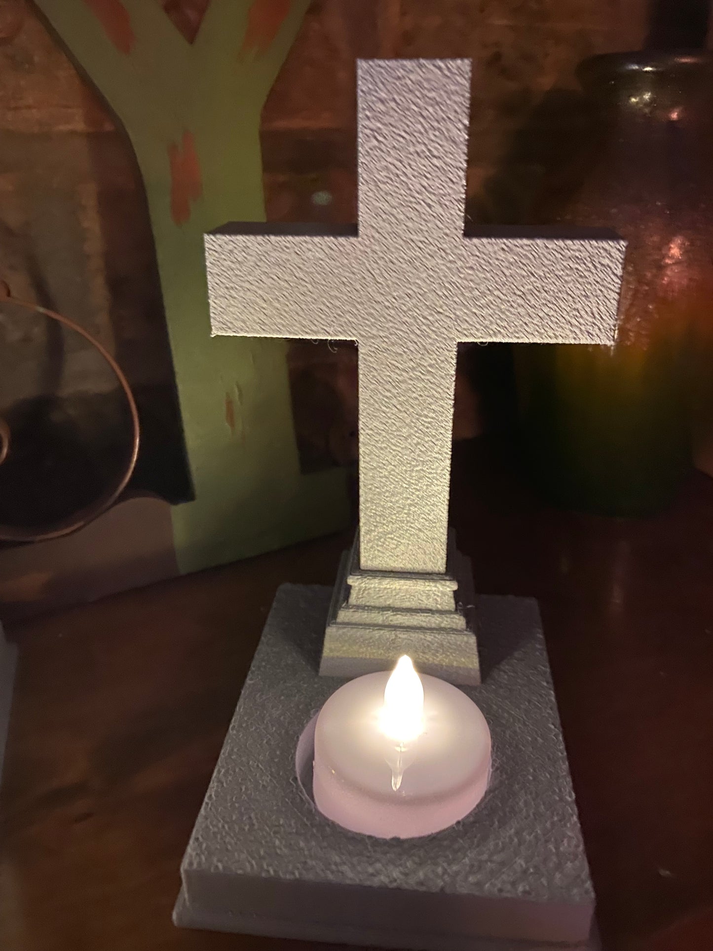 Stone-look cross grave marker on a stepped pedestal with an LED tea light at its base