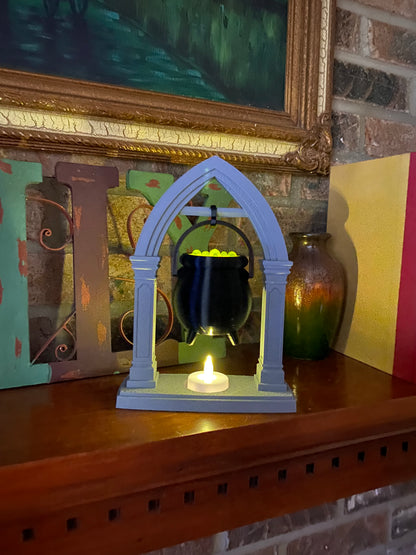 Hanging cauldron tea light holder on a wood mantel, LED tea light flickering in the stone-look base beneath the black cauldron
