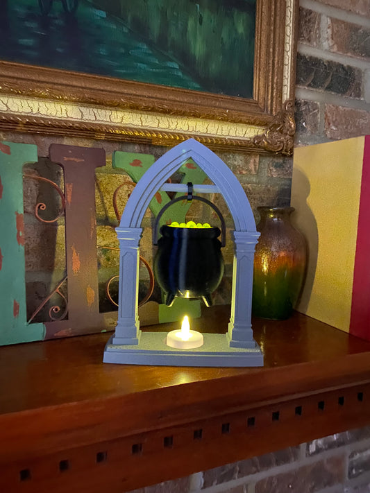 Hanging cauldron tea light holder on a wood mantel, LED tea light flickering in the stone-look base beneath the black cauldron