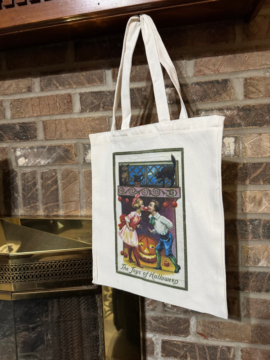 White tote bag with a Halloween design hanging on a mantle.
