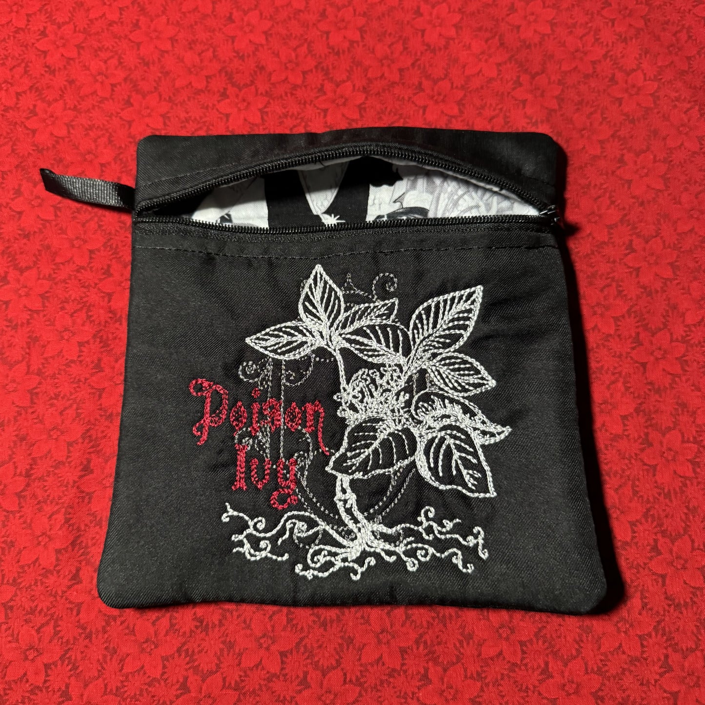 Black zippered pouch with silver Poison Ivy botanical embroidery and red gothic lettering
