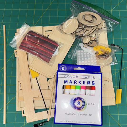 Crafting supplies including markers, wooden pieces, and tools on a green cutting mat.