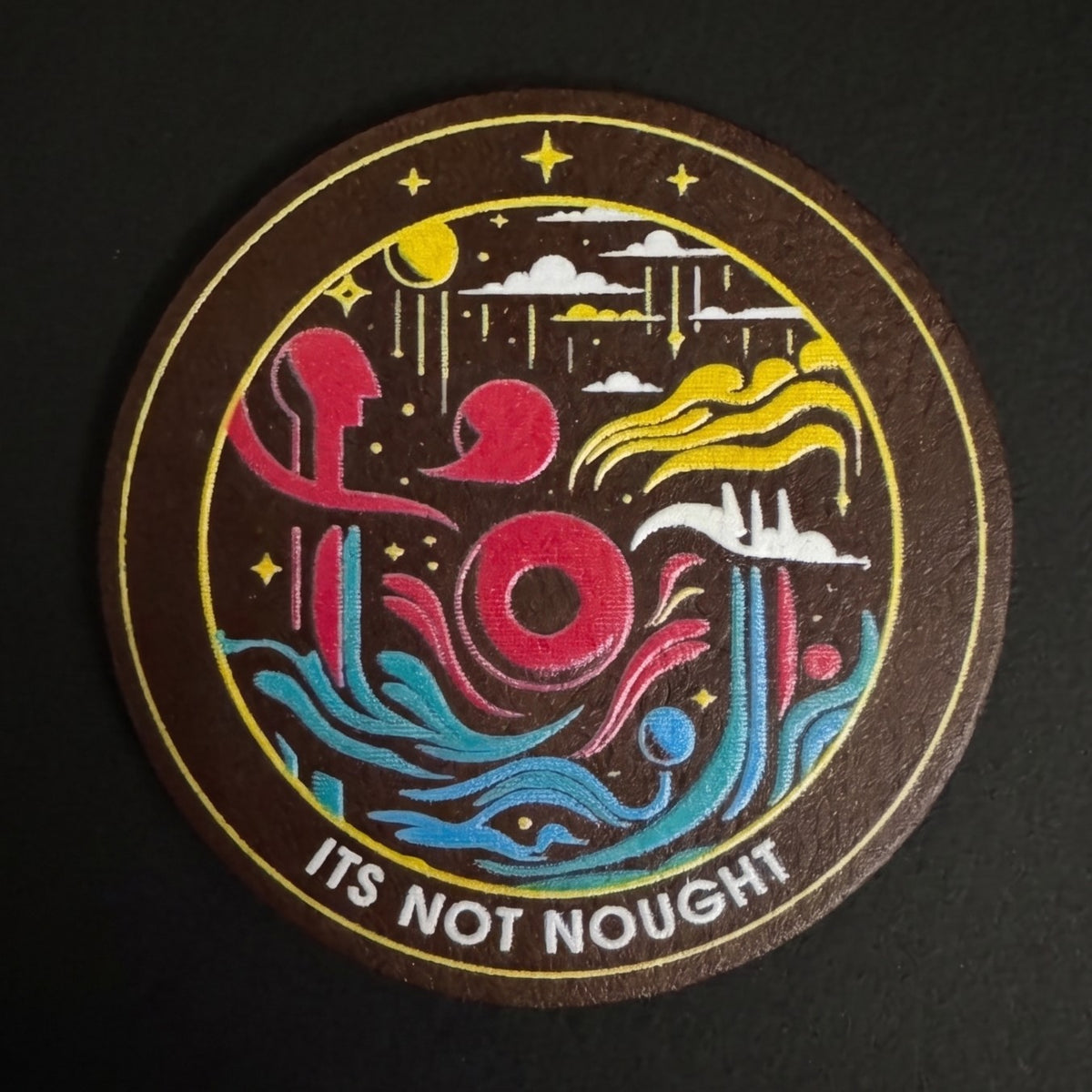 Its Not Nought logo UV printed in full color with white ink on a round brown faux leather patch
